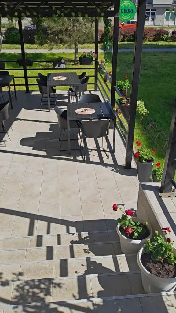 Outdoor garden of Aloo Aloo Pizzeria in Sremska Mitrovica – tables under the pergola with flowers