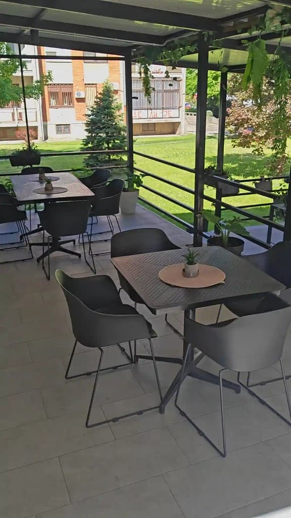 Unutrašnjost letnje bašte Aloo Aloo Picerije – stolovi i fotelje pod pergolom